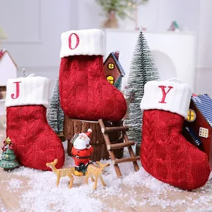 Set aus drei roten gestrickten Weihnachtssocken mit JOY-Buchstaben in einer Festzene