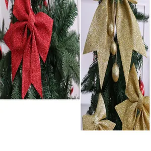 Detail van feestelijke rode en gouden glitter kerststrikken op een groene dennenboomtak