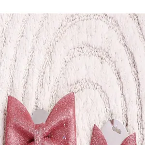 Gedetailleerd macrozicht op roze glitter kerststrikken op beige pluche tapijtachtergrond