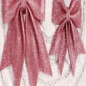 Detail van twee roze glinsterende kerststrikken op een witte getextureerde achtergrond