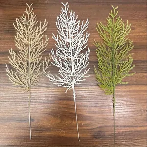 Detalle de ramas de pino de Navidad artificiales en oro, blanco y verde para decoración DIY.