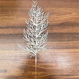 Primer plano de una rama de cedro artificial blanca para decoración navideña sobre madera
