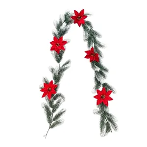 Artificial pine garland with red poinsettia flowers and snow frosting for Christmas decor