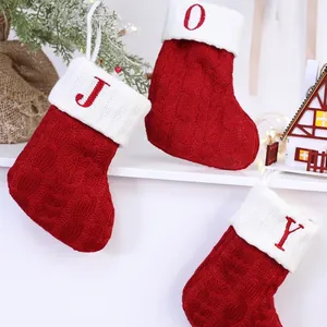 Nahaufnahme roter Strick-Weihnachtssocken mit weißen Umschlägen und JOY-Buchstaben