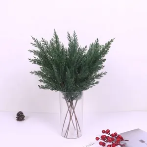 Detailed view of artificial green cypress branches in a clear glass vase for Christmas decor