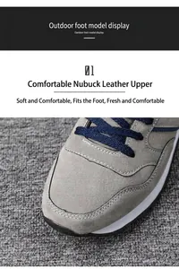 Detail of men's grey pigskin leather running shoes with navy blue laces and stitching.