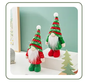 Detail of two sequined Christmas gnome figurines with striped hats on a white platform.