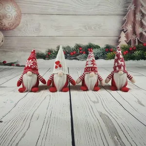Detailansicht von vier gestrickten Weihnachtswichteln mit festlichen Mustern auf hellem Holz.