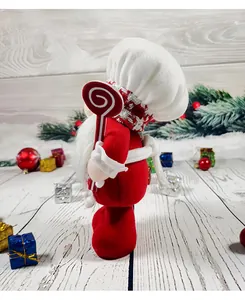 Detailed side view of a Christmas chef gnome doll holding a big red lollipop ornament