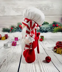 Side view of a festive plush Christmas gnome doll holding a red and white candy cane ornament