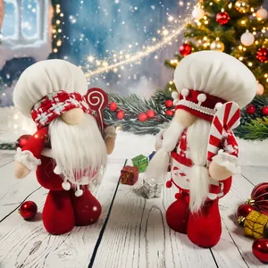 Pair of adorable Christmas chef gnome plush dolls with candy props in snowy scene.