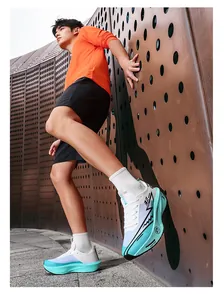 Modello con scarpe da corsa maratona bianche e verde acqua con suola spessa in carbonio.