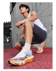 Modello maschile che indossa scarpe da corsa bianche e arancioni su pista