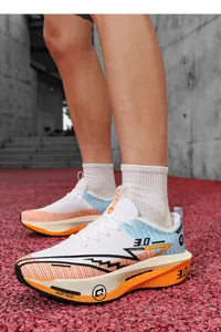 Vista laterale dettagliata di scarpe da corsa bianche e arancioni su una pista atletica.