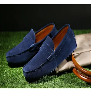 Primer plano de mocasines de ante azul para hombre con detalle de correa penny y costura.