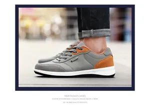 Close-up of grey and orange men's walking shoes shown on an outdoor pavement surface.