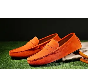 Mocassins en daim orange vif pour hommes présentés dans un cadre extérieur décontracté.