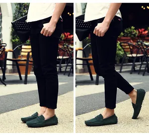 Mocasines de ante verde oscuro para hombre con pantalones negros en una vista de calle exterior