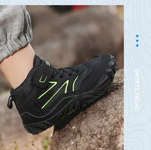 Detailopname van zwarte en groene kinderwandelschoenen met stevige zolen op rotsen.