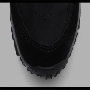 Close-up of black outdoor sports shoe toe showing stitching and textured rubber sole.
