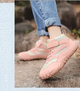 Detailweergave van roze kinderwandelschoenen die op rotsachtig terrein worden gedragen