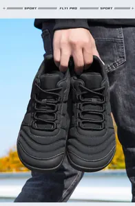 Vista detallada de zapatillas casuales negras ligeras con punta ancha en las manos.