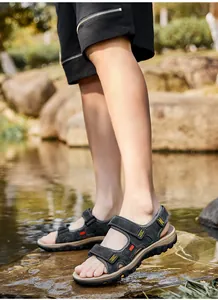 Close-up of men's genuine leather sandals with adjustable straps in a natural outdoor setting.