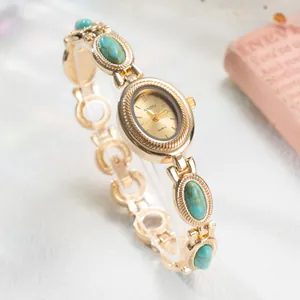 Gros plan d'une montre bracelet dorée vintage avec incrustations de turquoise et cadran.