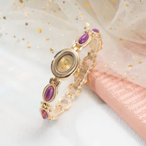 Vue détaillée d'une montre-bracelet dorée avec pierres violettes et cadran délicat.