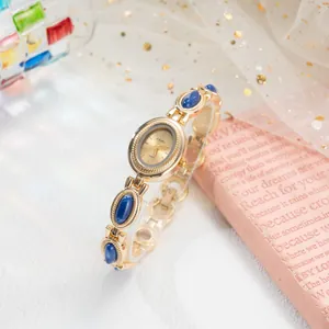 Montre-bracelet élégante dorée avec accents en pierre bleue et détails design vintage.