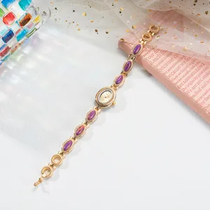 Gros plan d'une montre-bracelet dorée pour femme au style vintage avec pierres violettes.