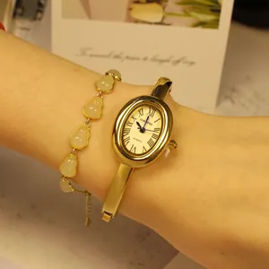 Elegante reloj de pulsera ovalado en oro rosa combinado con una pulsera de jade en la muñeca.
