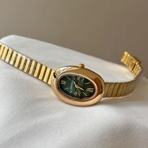 Gros plan d'une montre vintage dorée pour femme avec cadran ovale vert et bracelet