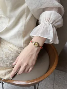 Montre-bracelet vintage en or avec pierres rouges portée au poignet élégant.