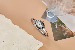 Elegante zilveren ovale vintage horloge met Romeinse cijfers op warme achtergrond.