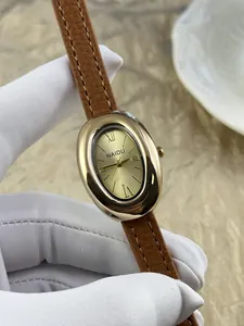 Detailopname van elegant ovaal goudkleurig dameshorloge met bruine leren band en Romeinse cijfers.
