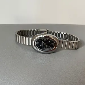 Montre vintage pour femme avec cadran ovale noir et bracelet argenté.