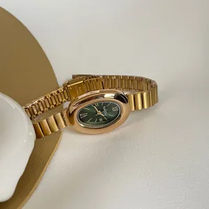 Vue détaillée d'une montre vintage dorée pour femme avec un cadran vert ovale élégant.