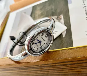 Primer plano de un reloj de pulsera ovalado plateado con números romanos blanco