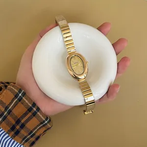 Élégante montre vintage dorée pour femme avec cadran ovale tenue dans la main