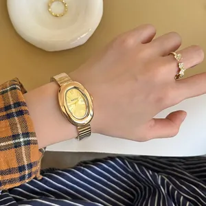 Vue détaillée montrant l'élégant cadran ovale doré et le bracelet en métal au poignet