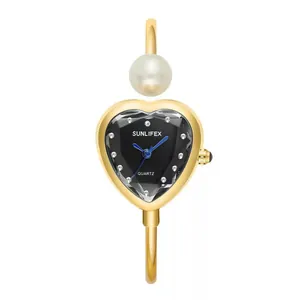 Detalle del reloj brazalete de oro SUNLIFEX en forma de corazón con perla e índices de cristal.