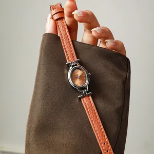 Close-up of an elegant oval women's quartz watch featuring a textured tan leather strap