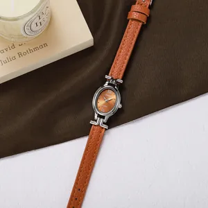 Close-up of elegant oval women's quartz watch with orange leather strap and dial.