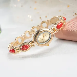 Gros plan d'une montre-bracelet dorée vintage avec pierres rouges et cadran ovale.