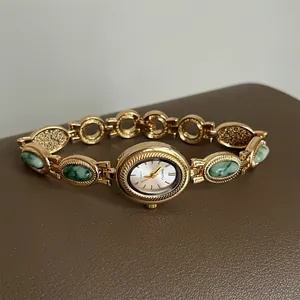 Détail d'une montre bracelet dorée de style vintage avec d'élégantes pierres vertes