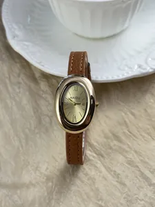 Detailopname van luxe retro ovaal goudkleurig horloge met elegante bruine leren band