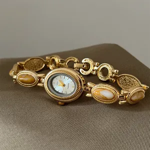 Vue détaillée d'une montre-bracelet dorée vintage avec incrustations de pierres sur tissu