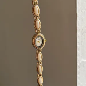 Vue détaillée d'une montre bracelet vintage dorée avec d'élégants maillons crème