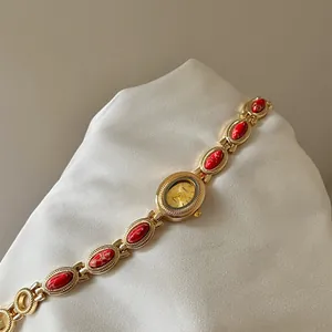 Gros plan d'une montre bracelet dorée vintage avec incrustations de pierres rouges